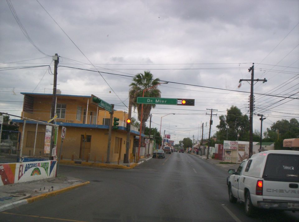 Street view with yellow building, palm tree, and traffic light. A white pickup truck is visible on the right