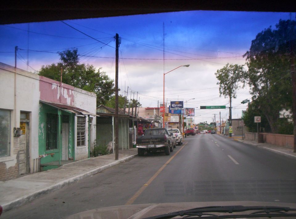 Street view from inside a vehicle, showing parked trucks and buildings