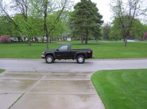 2000 Chevrolet Tahoe - A black pickup truck is seen from the side, parked on a residential street.