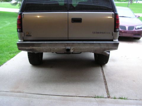 2000 Chevrolet Tahoe - The rear of a Chevrolet SUV is shown with a custom aftermarket bumper and a purple sedan in the background.