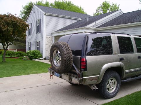 2000 Chevrolet Tahoe - This SUV, likely from the 1990s, is parked in a suburban driveway with a spare tire mounted externally on the rear.