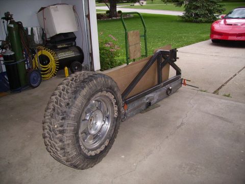 2000 Chevrolet Tahoe - A custom-built trailer frame, a large spare tire, sits in a driveway outside a garage.