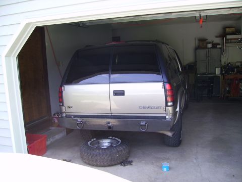 2000 Chevrolet Tahoe - The rear of a 2000 Chevrolet Tahoe is visible inside a garage, with a spare tire lying on the floor.