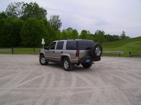 2000 Chevrolet Tahoe - This silver SUV, likely a 2000 Chevrolet Tahoe, is viewed from the rear with a spare tire mounted on a custom bumper.