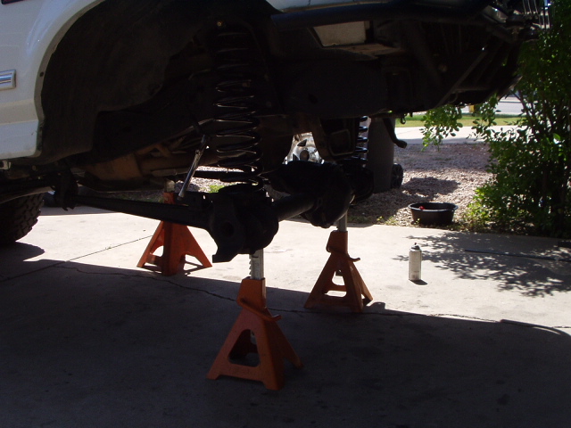 White Bronco on orange jack stands showing front axle and suspension underneath