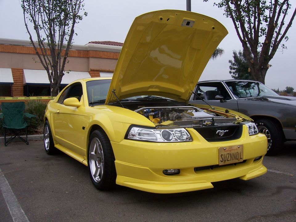 Yellow 2002 Ford Mustang with hood open, parked next to another car
