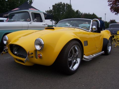 2002 Ford Mustang - A yellow convertible sports car is parked next to a white and teal pickup truck.