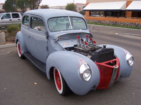 2002 Ford Mustang - This custom hot rod features a prominent red grille and exposed engine with multiple exhaust pipes.