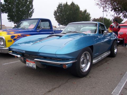 2002 Ford Mustang - A classic blue sports car, possibly a 1967 Corvette, is parked next to a custom pickup truck.