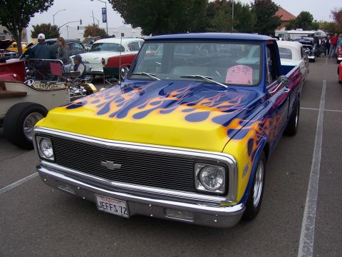 2002 Ford Mustang - A custom Chevrolet pickup truck with vibrant flame graphics is parked at an outdoor event.