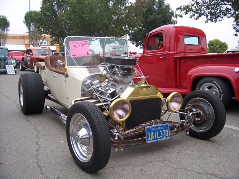 2002 Ford Mustang - A custom hot rod, likely a Ford Model T, is displayed with its powerful engine exposed, parked alongside a vintage red pickup truck.