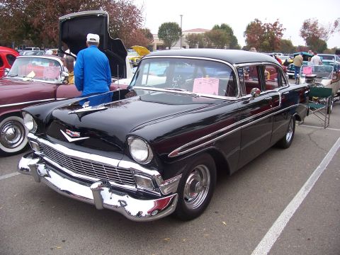 2002 Ford Mustang - A black 1956 Chevrolet Bel Air is parked at an outdoor car show next to other vehicles.
