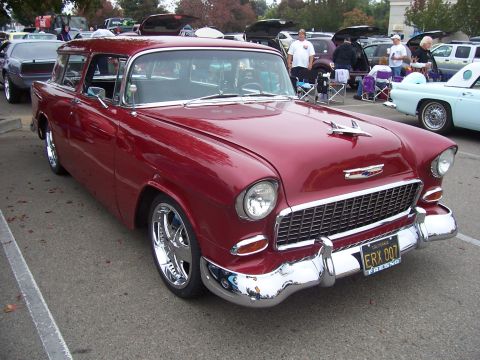 2002 Ford Mustang - A classic red 1955 Chevrolet Nomad wagon is displayed at an outdoor event, chrome wheels and a distinctive grille.
