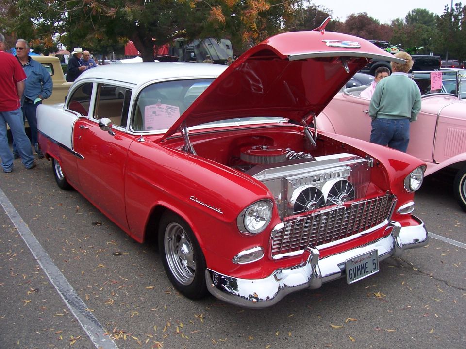 Red and white 1955 Chevrolet Bel Air with hood open, showing engine and chrome radiator