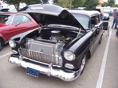 2002 Ford Mustang - A classic black 1955 Chevrolet Nomad station wagon is displayed with its hood open, revealing the engine compartment.
