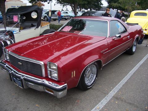 2002 Ford Mustang - A red El Camino is parked at an outdoor car show with other vehicles visible.
