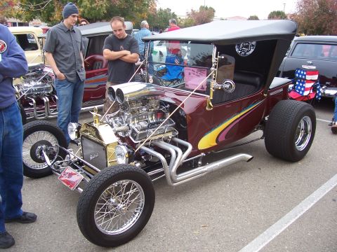 2002 Ford Mustang - A custom hot rod with a prominent engine is displayed at an outdoor event.