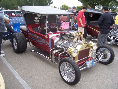 2002 Ford Mustang - A custom hot rod with a prominent engine and unique paint scheme is displayed at an outdoor event.