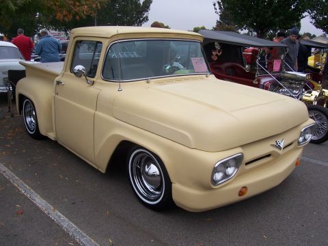 2002 Ford Mustang - A customized tan pickup truck with a lowered stance and chrome wheels is parked at an outdoor event.