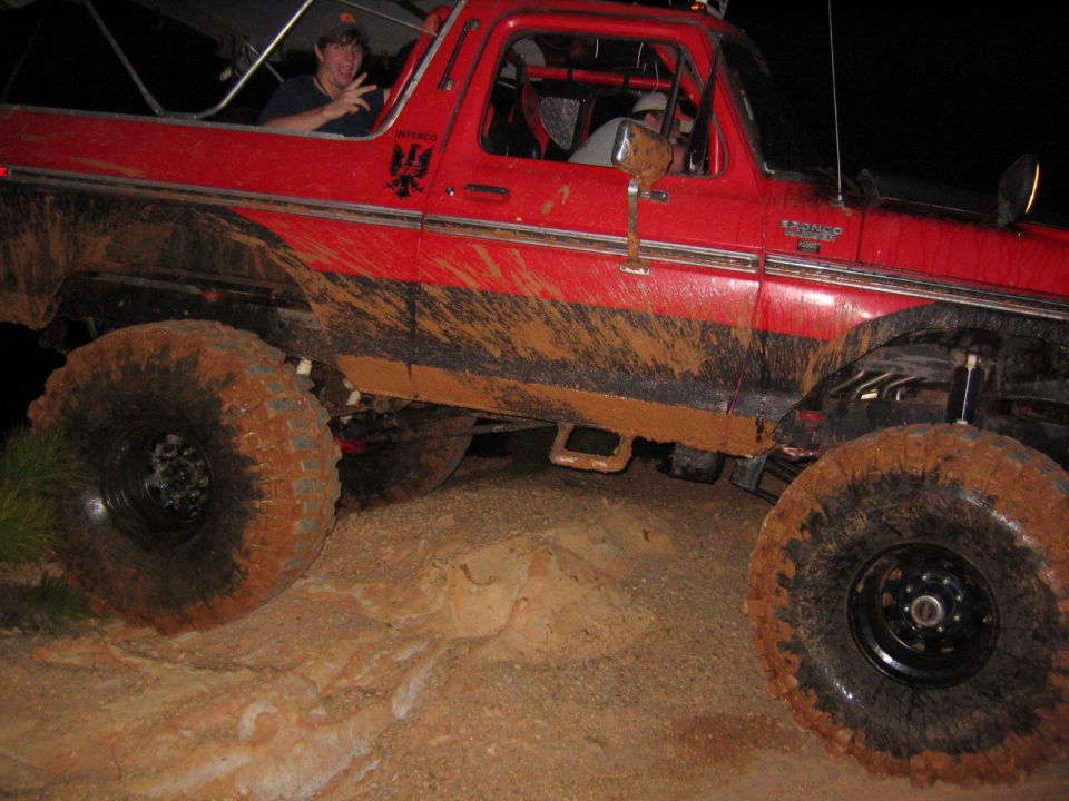 Red 1979 Ford Bronco with mud on tires and body