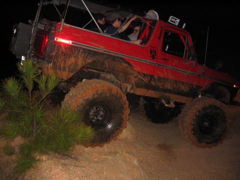 1979 Ford Bronco - Muddy 1979 Ford Bronco navigates an off-road trail in the dark.