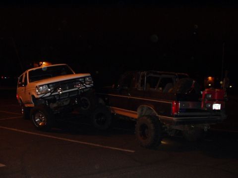 1993 Ford Bronco - Two modified Ford Broncos are seen at night, with one lifted higher than the other.