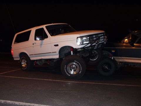 1993 Ford Bronco - This lifted 1993 Ford Bronco features a custom front bumper and grille, with another vehicle visible in the background.