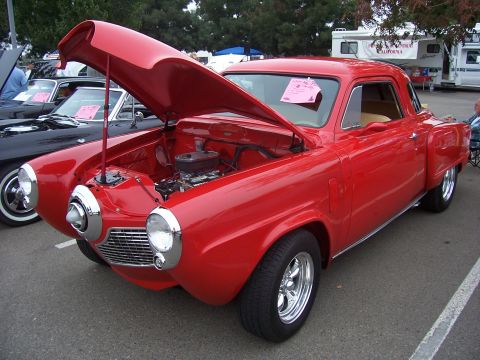 2002 Ford Mustang - A classic red Studebaker Champion is displayed with its hood open, revealing the engine bay.