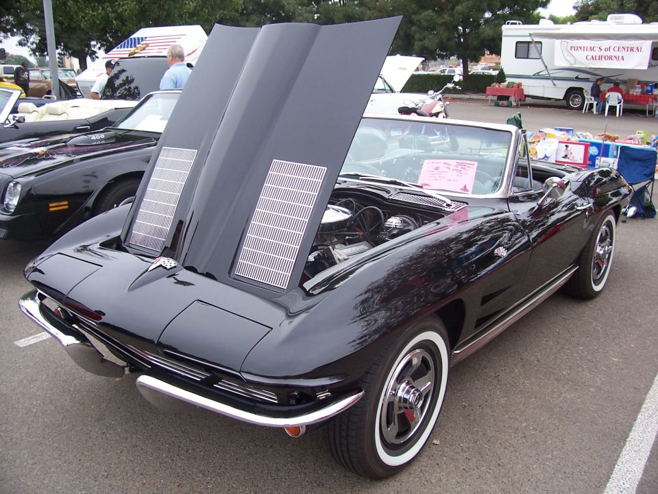 Black convertible with hood open, showing engine and chrome details