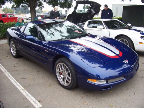 2002 Ford Mustang - A blue Chevrolet Corvette C5 is parked next to a white Ford GT, with its doors open.
