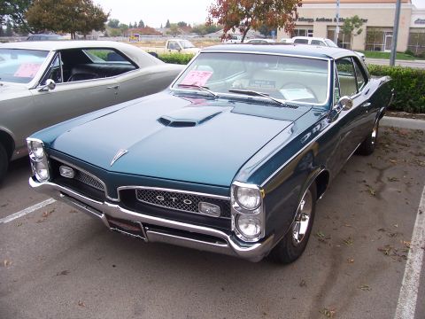 2002 Ford Mustang - A teal 1967 Pontiac GTO is parked next to another classic car.