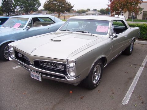 2002 Ford Mustang - A silver 1966 Pontiac GTO is parked next to a blue car in a parking lot.