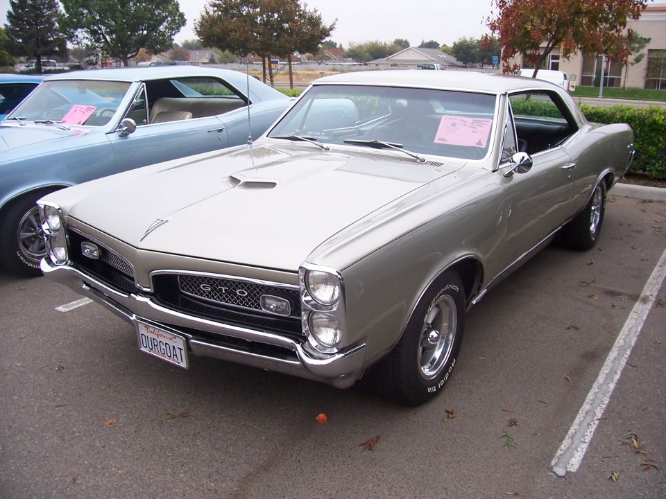 Silver 1966 Pontiac GTO with a blue car parked next to it