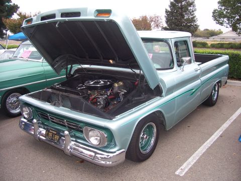 2002 Ford Mustang - Light blue 1964 Chevrolet C10 pickup truck with hood open, parked next to a green car.