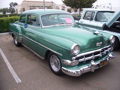 2002 Ford Mustang - A classic green Chevrolet sedan is parked next to a pickup truck, with a person visible in the driver's seat of the sedan.