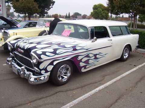 2002 Ford Mustang - A white 1955 station wagon customized with purple and white flame graphics is parked at an outdoor event.