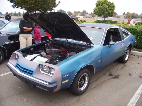 2002 Ford Mustang - A blue coupe with its hood open is displayed next to another vehicle, with people looking at the engine.