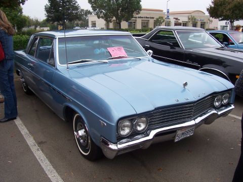 2002 Ford Mustang - A light blue 1964 Buick sedan is parked next to a black car.