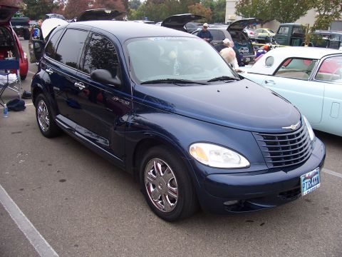 2002 Ford Mustang - A dark blue Chrysler PT Cruiser is parked at an outdoor event with other vehicles.