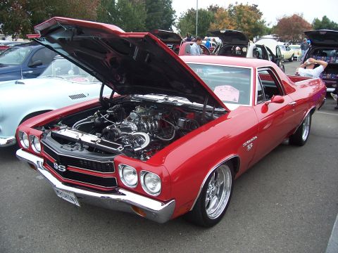 2002 Ford Mustang - A red El Camino SS is displayed with its hood open, revealing the engine, at an outdoor car show.