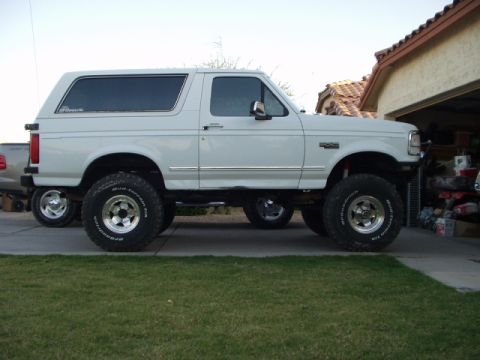 1993 Ford Bronco - Side view of a white Ford Bronco with off-road tires and a lifted suspension.