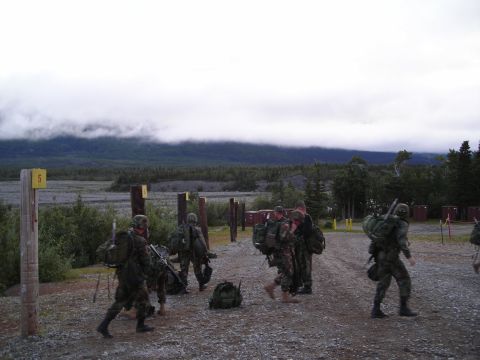 2003 Jeep TJ - Military personnel with gear move through a training area with a mountainous backdrop.