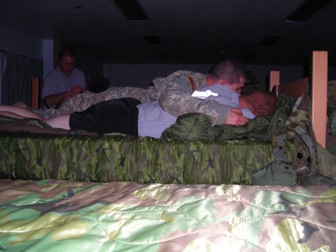 2003 Jeep TJ - Several individuals in military uniforms are seen on bunk beds, with camouflage bedding and sleeping bags visible.