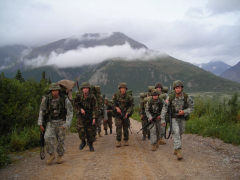 2003 Jeep TJ - Soldiers are on a march through a mountainous terrain under a cloudy sky.