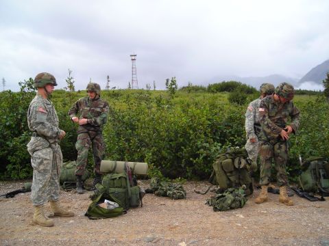 2003 Jeep TJ - Military personnel prepare their equipment outdoors under a cloudy sky.