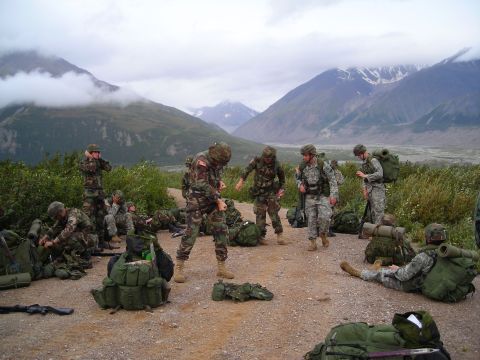 2003 Jeep TJ - A group of soldiers prepares for an outdoor excursion amidst a scenic mountain backdrop.
