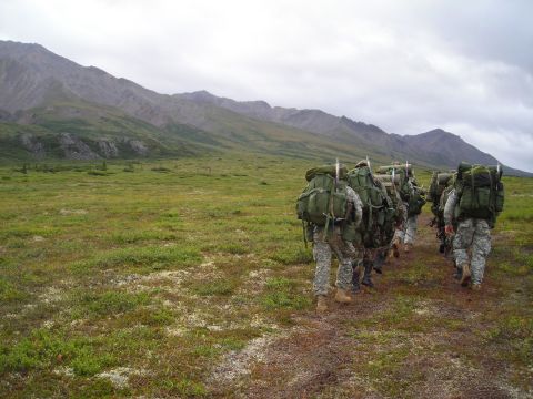 2003 Jeep TJ - A group of soldiers trek through a vast, open landscape with mountains in the background under an overcast sky.