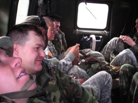 2003 Jeep TJ - Several soldiers are seated inside a vehicle, some looking towards the camera and others out a window.