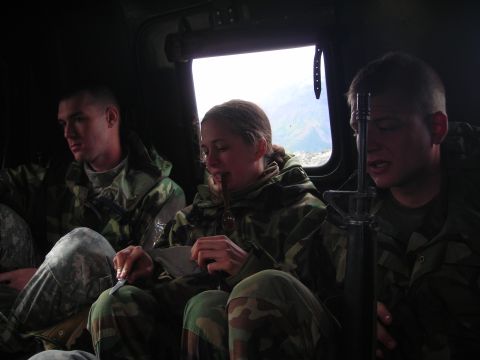 2003 Jeep TJ - Three individuals in camouflage uniforms are seated inside a vehicle, with one person eating.