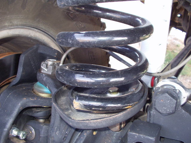 Black coil spring in lower perch of vehicle suspension, close-up
